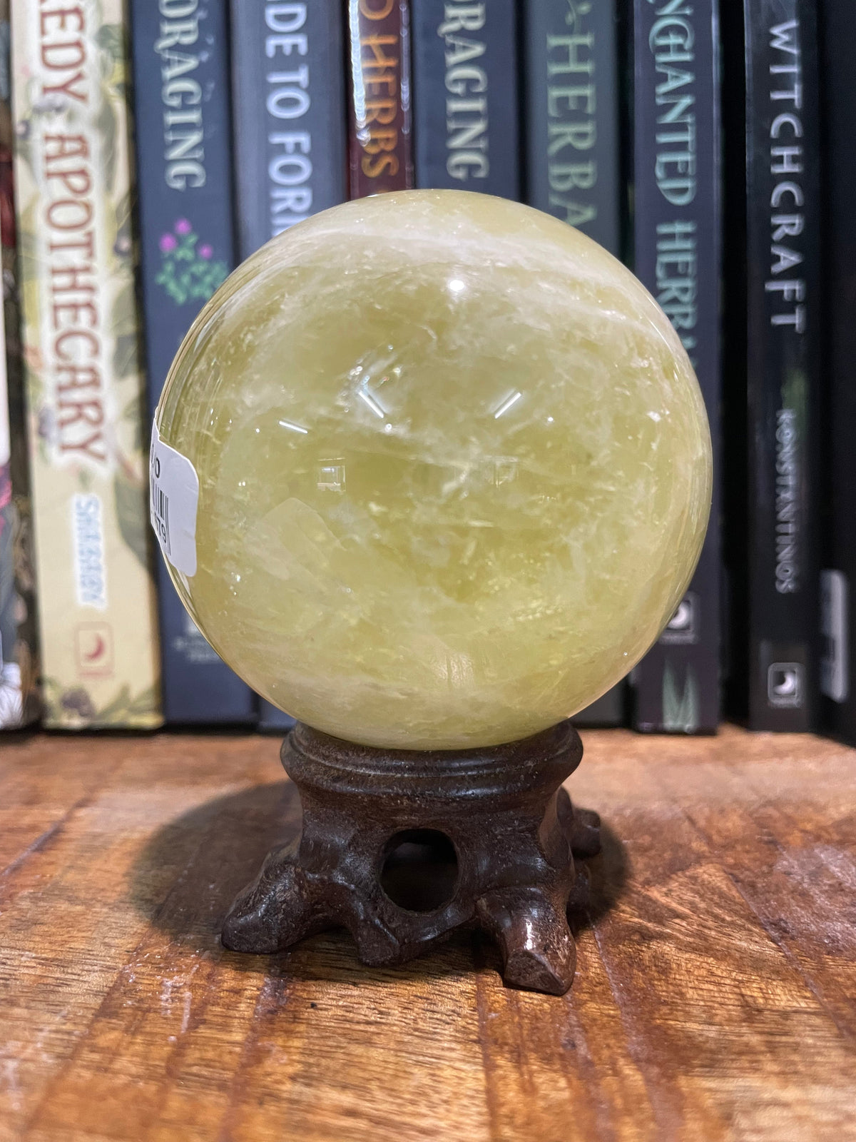 A polished Citrine crystal sphere displayed on a wooden stand, with beautiful internal rainbow patterns visible.